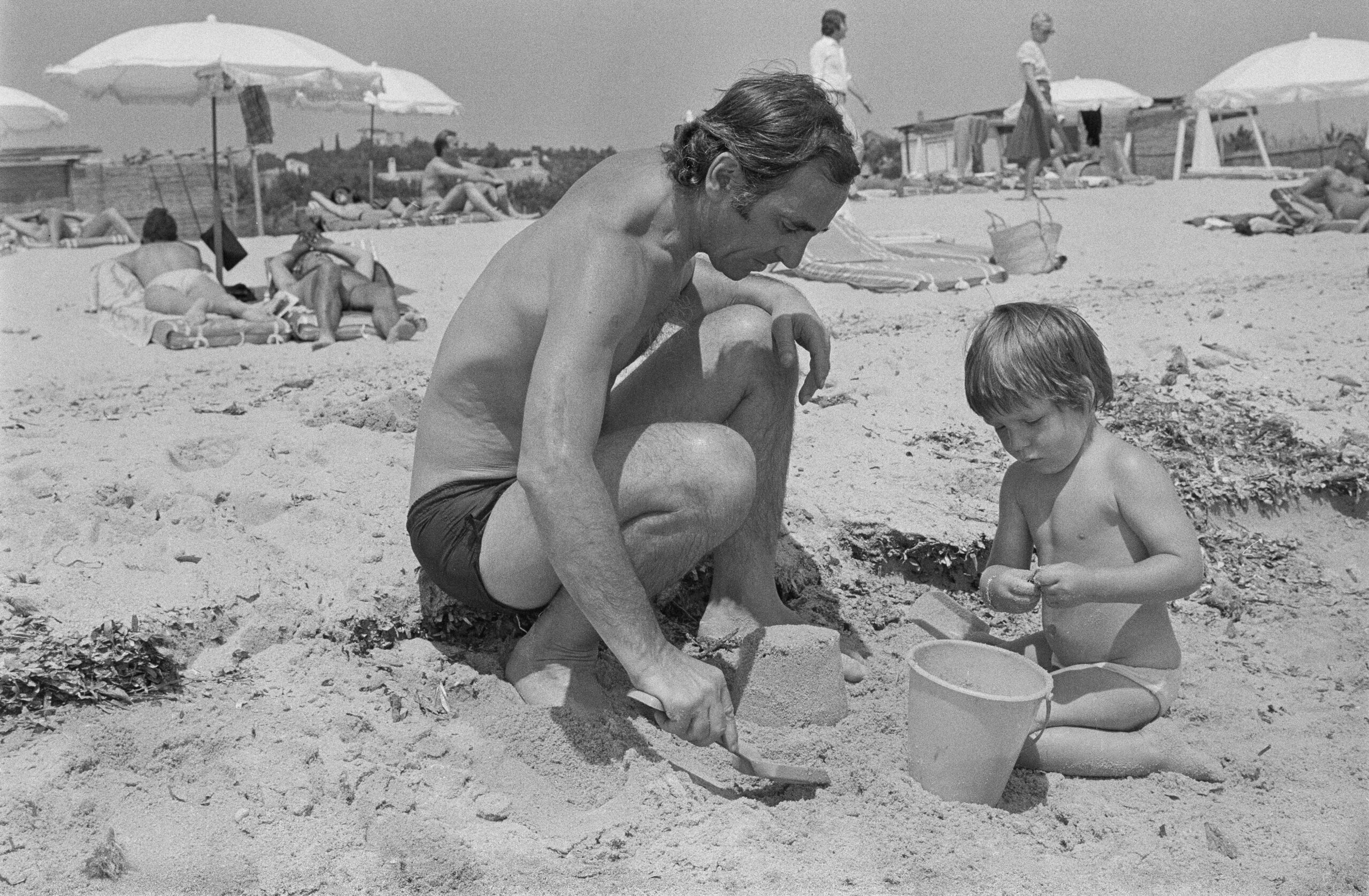 Charles Aznavour construyendo un castillo de arena